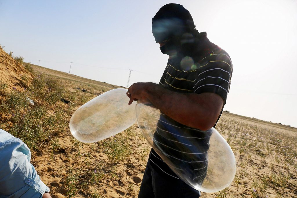 A masked Palestinian prepares a balloon that will be attached to flammable materials to be launched into Israel near the Israeli Gaza border, in Rafah in the southern Gaza Strip on June 17, 2018. (Abed Rahim Khatib/Flash90)