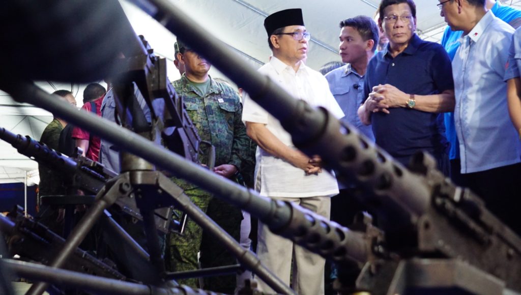 President Duterte surveys the “decommissioning” of former rebel fighters and their weapons