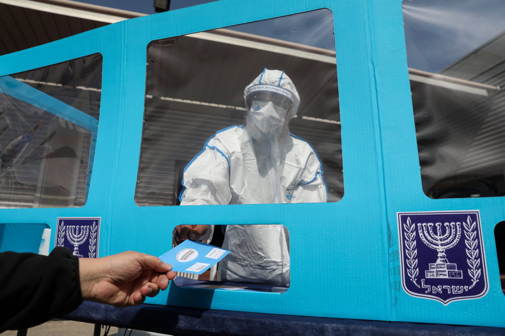 A worker of the Central Election Commission in Israel wearing a full protective suit during a media demonstration of special polling stations for people infected with coronavirus as part of  preparation for the upcoming Israeli general elections, in Shoham, Israel, 23 February 2021. Israel is expected to hold legislative elections on 23 March 2021 to elect the members of the 24th Knesset.  EPA/ABIR SULTAN