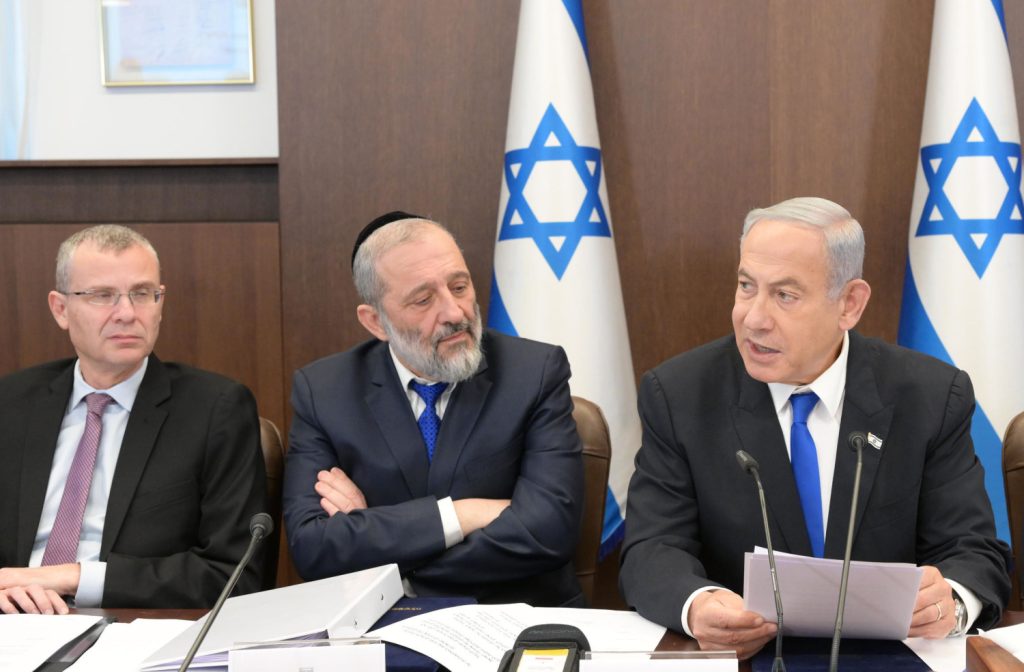 Netanyahu and Deri (right and centre), both of whom face legal troubles, sit alongside Justice Minister Yariv Levin (left), the author of controversial proposed judicial reforms, at a cabinet meeting (Image: IGPO/Flickr)
