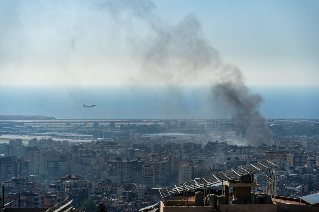 A plane takes off from Beirut International Airport as smoke rises from airstrike on Beirut southern suburbs, amid ongoing war between Hezbollah and Israel (Image: Ali Chehade Farhat/ Shutterstock)