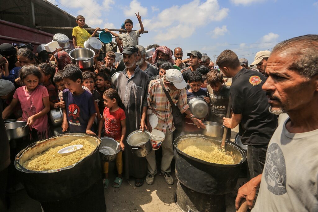 Palestinians receive meals from the charity kitchen in Khan Yunis, southern Gaza Strip, on August 21, 2025 (Image: Anas Mohammed/ Shutterstock)
