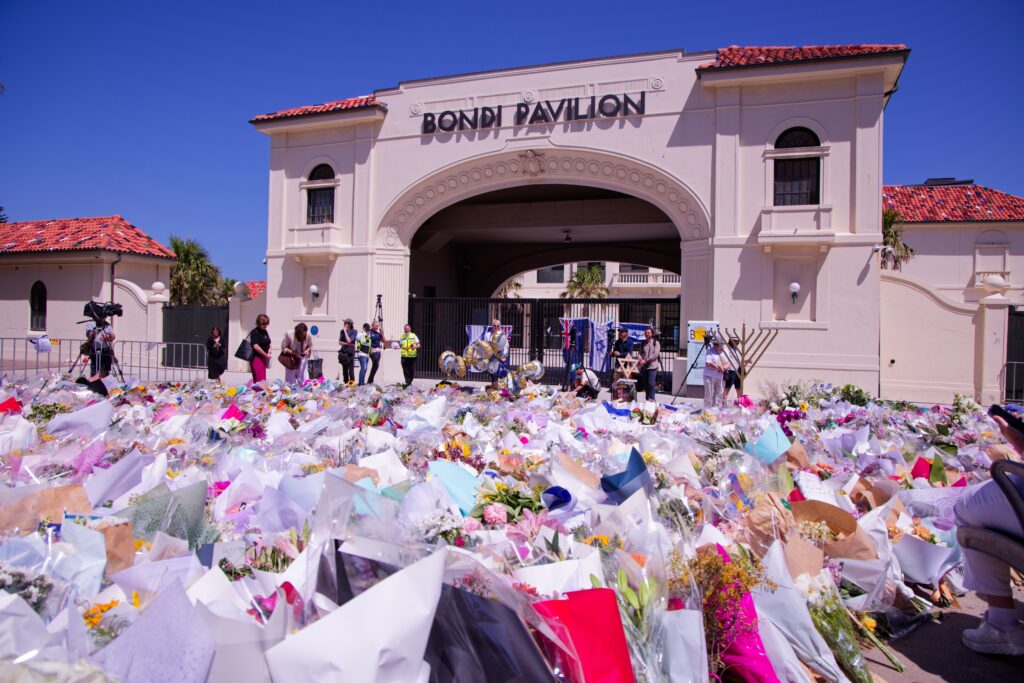 People gather at a flower memorial for the victims outside the Bondi Pavilion in Sydney (Image: Shutterstock)