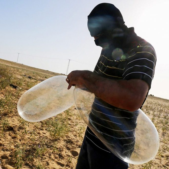 A masked Palestinian prepares a balloon that will be attached to flammable materials to be launched into Israel near the Israeli Gaza border, in Rafah in the southern Gaza Strip on June 17, 2018. (Abed Rahim Khatib/Flash90)