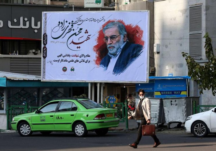 An Iranian man walks by a billboard of slain Iranian nuclear scientist Mohsen Fakhrizadeh in Tehran, on November 30, 2020. (AFP)