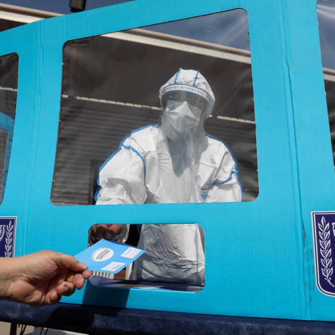 A worker of the Central Election Commission in Israel wearing a full protective suit during a media demonstration of special polling stations for people infected with coronavirus as part of  preparation for the upcoming Israeli general elections, in Shoham, Israel, 23 February 2021. Israel is expected to hold legislative elections on 23 March 2021 to elect the members of the 24th Knesset.  EPA/ABIR SULTAN