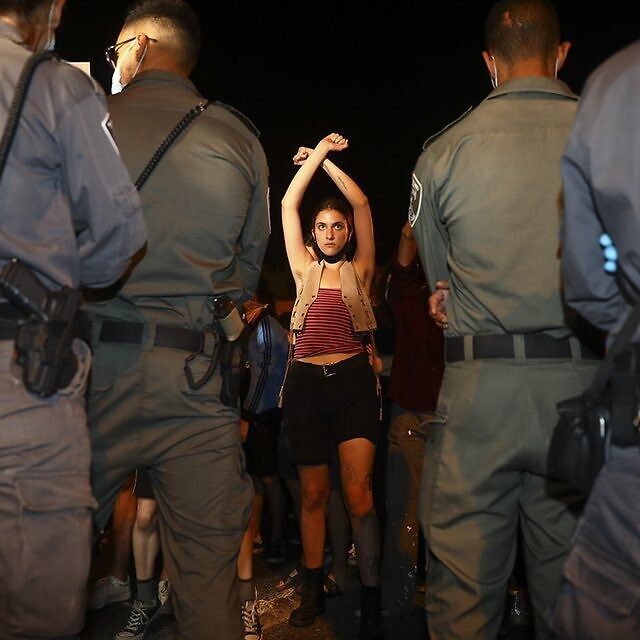 A protester faces police during a demonstration against Prime Minister Benjamin Netanyahu in Jerusalem, July 18, 2020 (AP Photo/Oded Balilty)