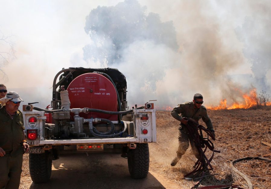 Israeli soldiers try to extinguish fire in an area close to the border between Israel and the Gaza Strip near southern Israeli Kibbutz of Nir Am (Credit: Gil Cohen Magen/ Shutterstock)