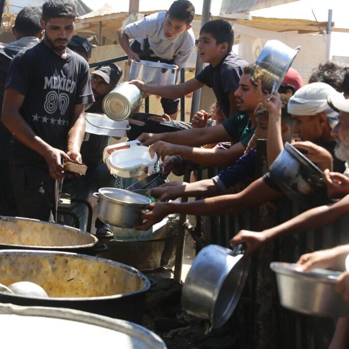 Displaced Palestinians receive food in Al-Mawasi, west of Khan Younis city in the southern Gaza Strip (Image: Anas Mohammed/ Shutterstock)