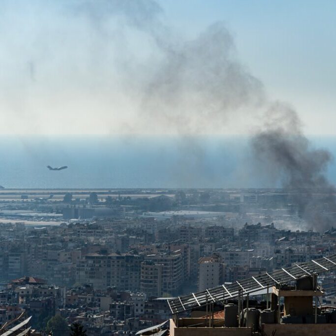 A plane takes off from Beirut International Airport as smoke rises from airstrike on Beirut southern suburbs, amid ongoing war between Hezbollah and Israel (Image: Ali Chehade Farhat/ Shutterstock)