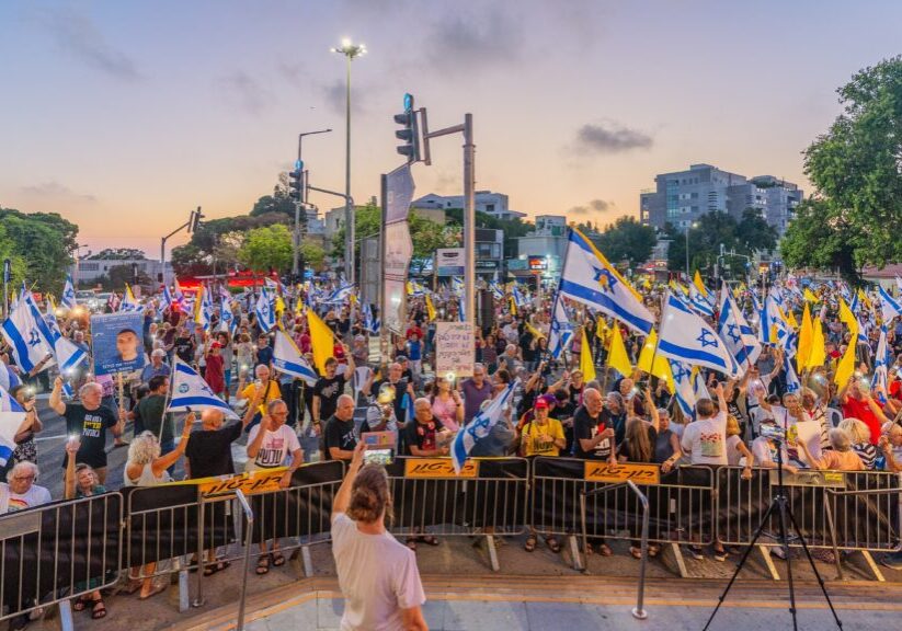 Israelis in Haifa with various signs and flags take part in a protest rally calling for end the war, completion of the hostage deal and new elections (Image: Shutterstock)