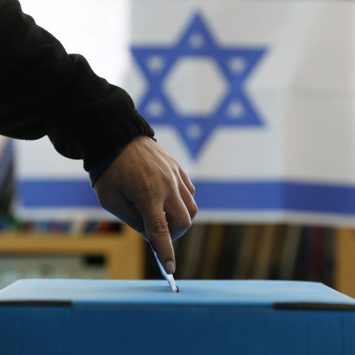An Israeli Flag Is Seen In The Background As A Man Casts His Ballot At A Polling In A West Bank Jewish Settlement, North Of Ramallah